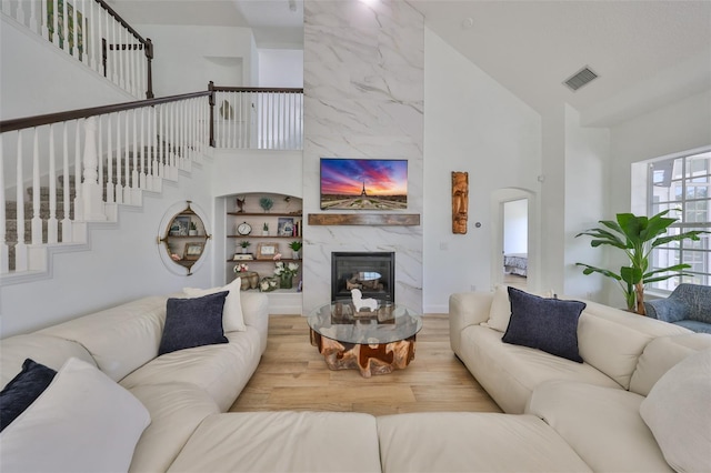 living area with visible vents, a high ceiling, wood finished floors, and a high end fireplace