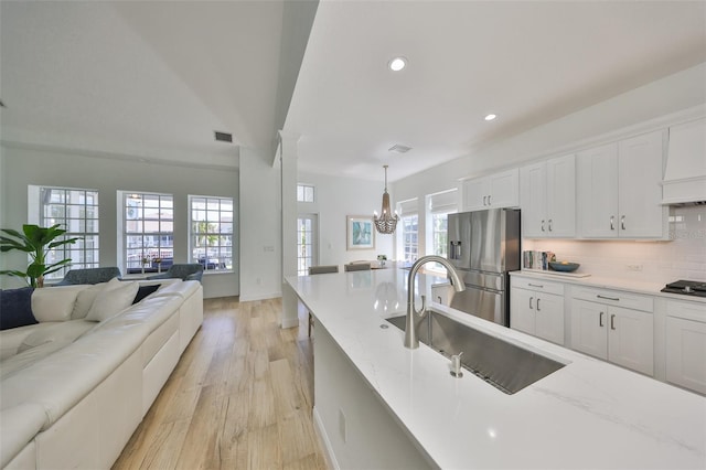 kitchen with tasteful backsplash, open floor plan, stainless steel appliances, white cabinetry, and a sink