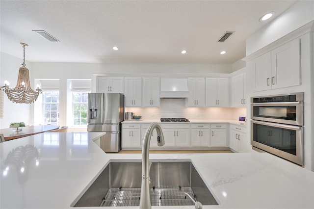 kitchen featuring stainless steel appliances, a sink, visible vents, and custom range hood