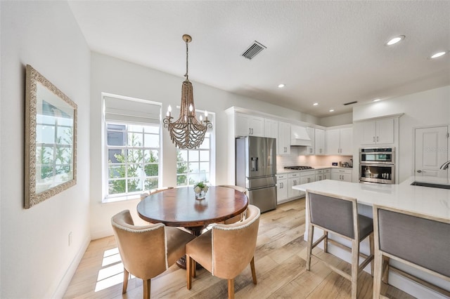 dining space featuring baseboards, visible vents, light wood-style floors, a chandelier, and recessed lighting