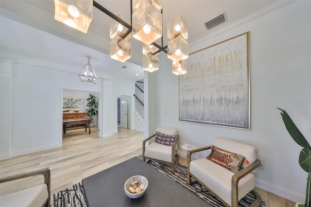 sitting room with arched walkways, visible vents, stairway, wood finished floors, and baseboards