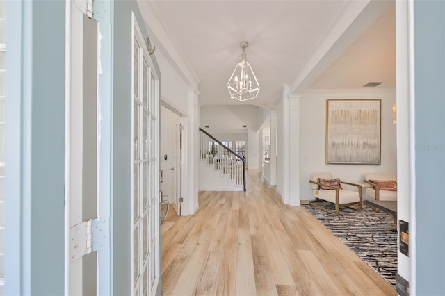 entrance foyer with light wood-style flooring, visible vents, stairs, ornamental molding, and an inviting chandelier