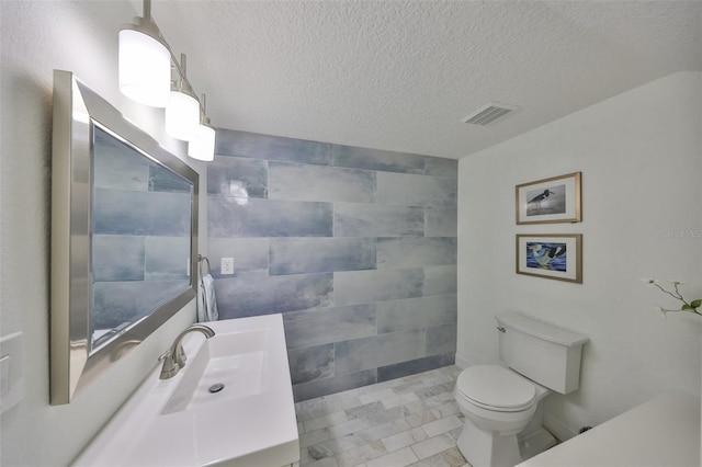 bathroom featuring toilet, visible vents, a textured ceiling, and vanity