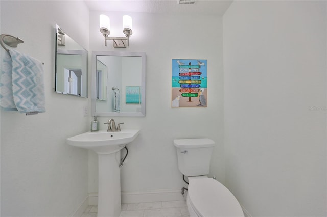 half bathroom with visible vents, a sink, toilet, and baseboards