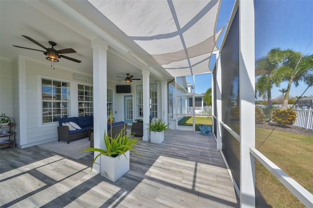 wooden deck featuring ceiling fan, a lanai, fence, an outdoor living space, and a lawn