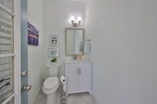 bathroom with toilet, baseboards, and vanity