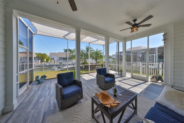 sunroom with plenty of natural light, a residential view, and a ceiling fan