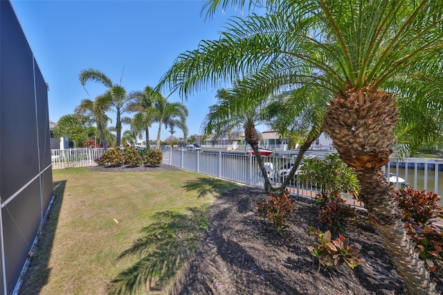 view of yard featuring glass enclosure, a water view, and fence