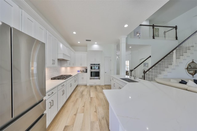 413 Islebay Dr, Apollo Beach, FL 33572 - kitchen with stainless steel appliances, a sink, light wood-style flooring, white cabinets, and backsplash