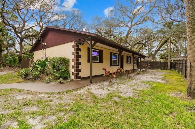 view of side of home featuring fence and stucco siding