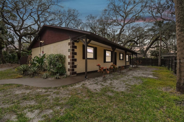 property exterior at dusk featuring fence and stucco siding