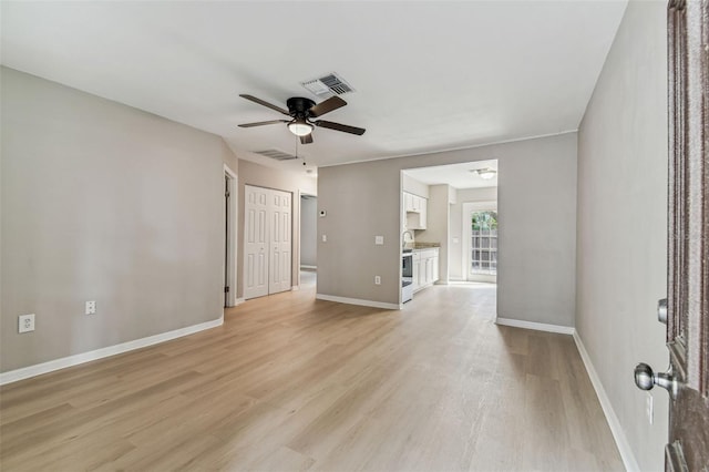 spare room with baseboards, light wood-type flooring, visible vents, and a ceiling fan