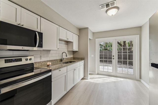 kitchen featuring light stone counters, visible vents, decorative backsplash, appliances with stainless steel finishes, and a sink