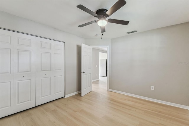 unfurnished bedroom featuring light wood-type flooring, freestanding refrigerator, visible vents, and baseboards