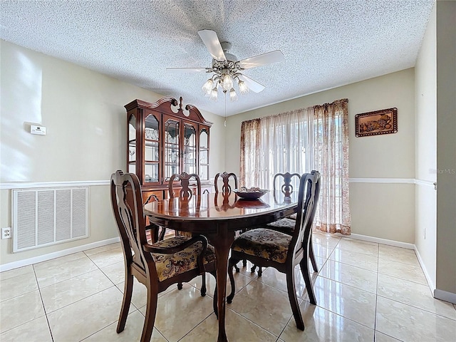 dining area with visible vents, a textured ceiling, light tile patterned floors, baseboards, and ceiling fan