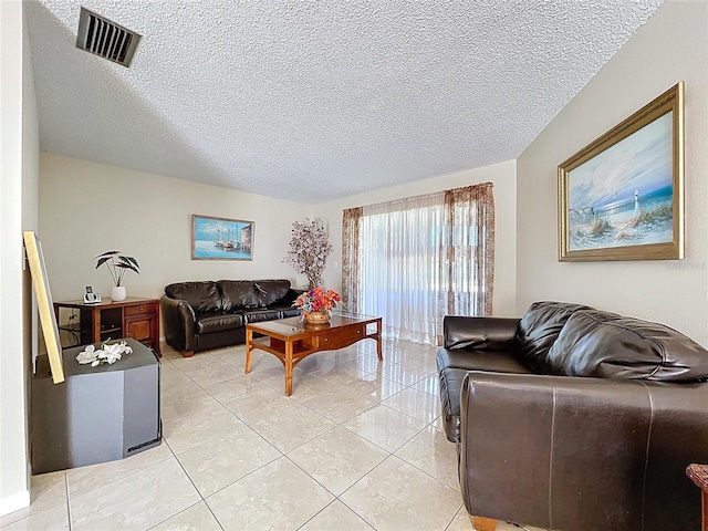 living area with light tile patterned floors, visible vents, and a textured ceiling