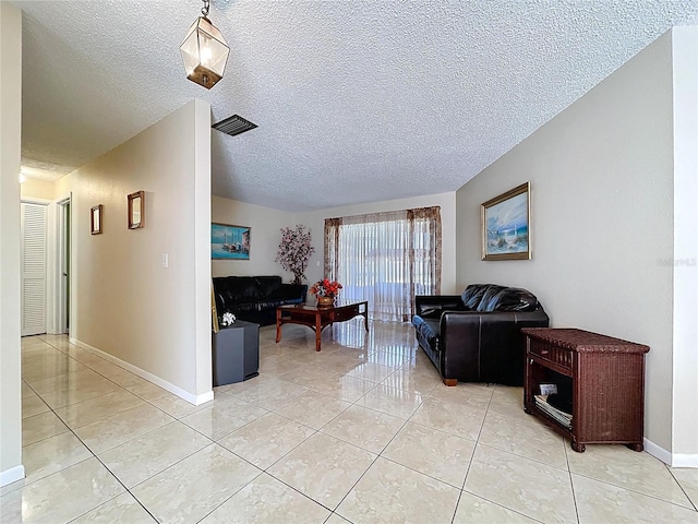 living area featuring light tile patterned flooring, visible vents, and a textured ceiling