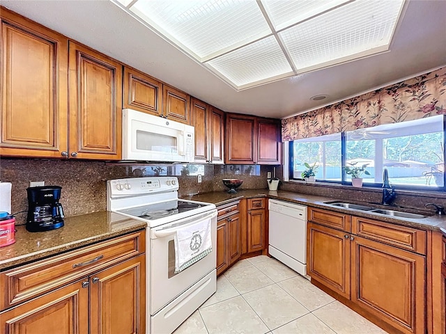 kitchen featuring a sink, white appliances, brown cabinetry, light tile patterned floors, and decorative backsplash