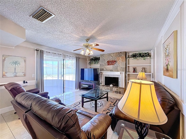 living area featuring a stone fireplace, light tile patterned flooring, visible vents, and a textured ceiling