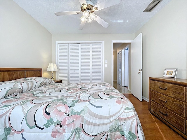 bedroom featuring visible vents, a textured ceiling, a closet, light wood finished floors, and ceiling fan