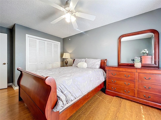 bedroom featuring a ceiling fan, baseboards, wood finished floors, a closet, and a textured ceiling