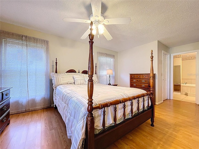 bedroom with connected bathroom, a textured ceiling, a ceiling fan, and light wood finished floors