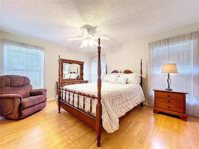 bedroom featuring light wood-style flooring, a ceiling fan, and a textured ceiling