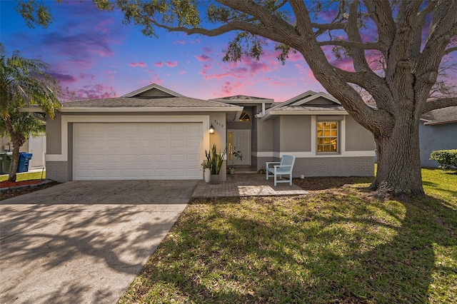 ranch-style house with a garage, brick siding, driveway, stucco siding, and a front lawn