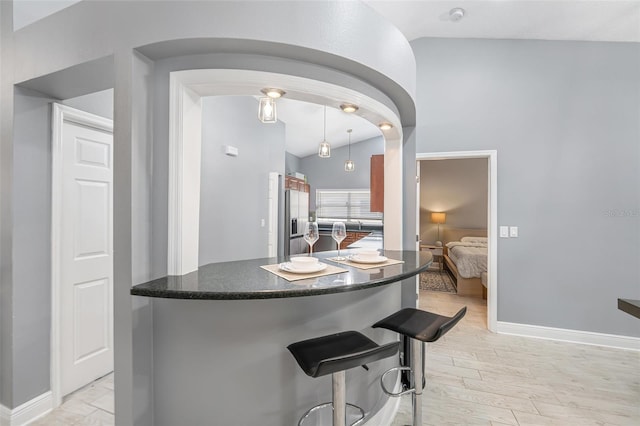 2519 Southern Oak Cir, Clearwater, FL 33764 - kitchen featuring arched walkways, stainless steel fridge with ice dispenser, light wood-style flooring, a breakfast bar, and vaulted ceiling