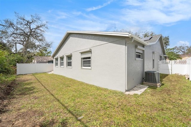 2519 Southern Oak Cir, Clearwater, FL 33764 - rear view of property featuring solar panels, stucco siding, a lawn, central AC unit, and a fenced backyard