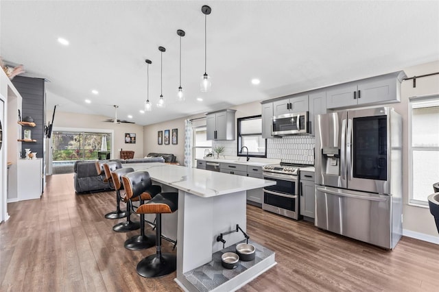31123 Stone Arch Ave, Wesley Chapel, FL 33545 - kitchen with light countertops, gray cabinetry, appliances with stainless steel finishes, open floor plan, and a kitchen breakfast bar