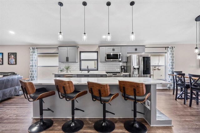 31123 Stone Arch Ave, Wesley Chapel, FL 33545 - kitchen featuring stainless steel appliances, dark wood-type flooring, light countertops, gray cabinets, and tasteful backsplash