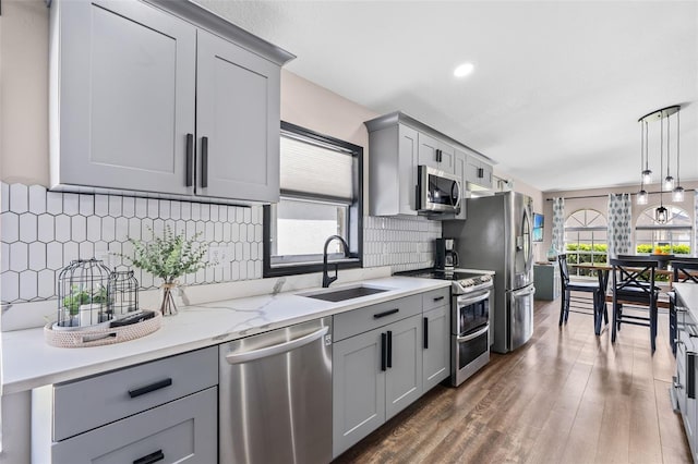 31123 Stone Arch Ave, Wesley Chapel, FL 33545 - kitchen featuring dark wood-style flooring, gray cabinets, hanging light fixtures, appliances with stainless steel finishes, and a sink
