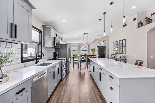 31123 Stone Arch Ave, Wesley Chapel, FL 33545 - kitchen featuring tasteful backsplash, a spacious island, dark wood-style floors, stainless steel appliances, and a sink