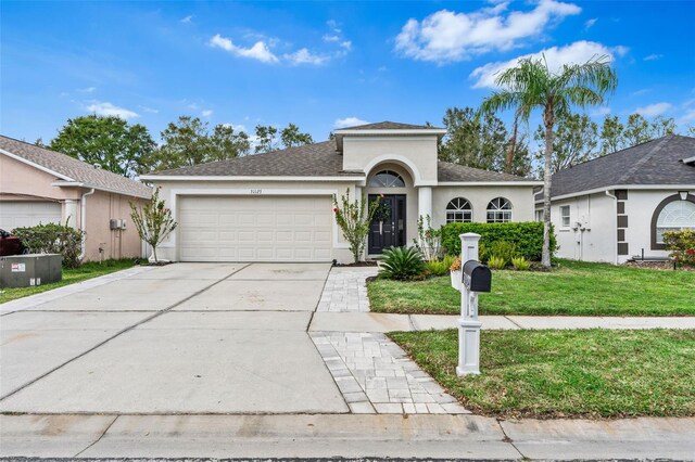 31123 Stone Arch Ave, Wesley Chapel, FL 33545 - view of front of property featuring an attached garage, concrete driveway, roof with shingles, stucco siding, and a front lawn