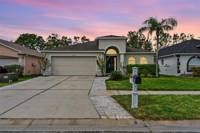 31123 Stone Arch Ave, Wesley Chapel, FL 33545 - view of front of home featuring concrete driveway, a yard, an attached garage, and stucco siding