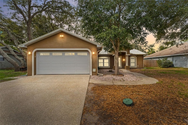 ranch-style home with an attached garage, driveway, and stucco siding