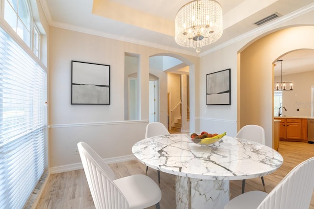 dining space featuring visible vents, a raised ceiling, stairs, light wood-style floors, and a notable chandelier