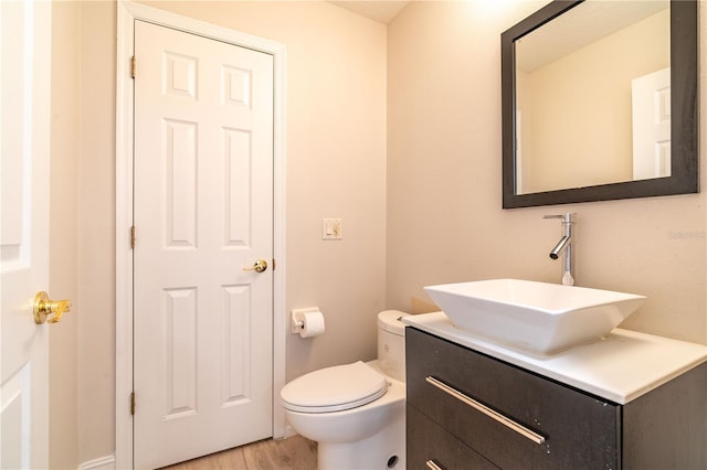 half bathroom featuring vanity, toilet, and wood finished floors