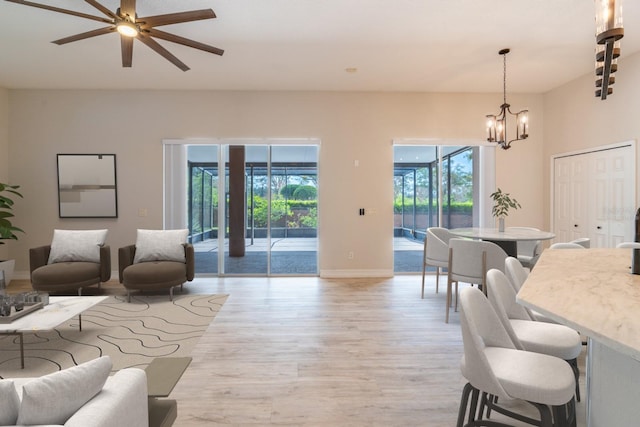 living area with baseboards, light wood finished floors, and an inviting chandelier