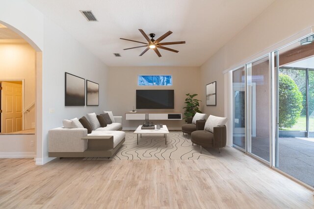 living room featuring arched walkways, ceiling fan, wood finished floors, visible vents, and baseboards