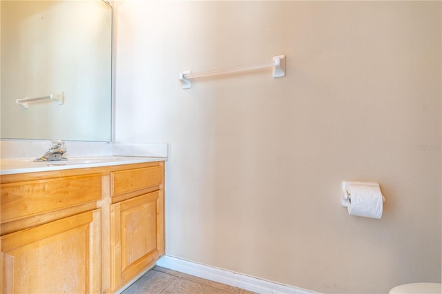 bathroom with toilet, tile patterned floors, baseboards, and vanity