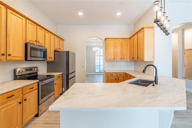 kitchen with stainless steel appliances, arched walkways, a sink, and backsplash