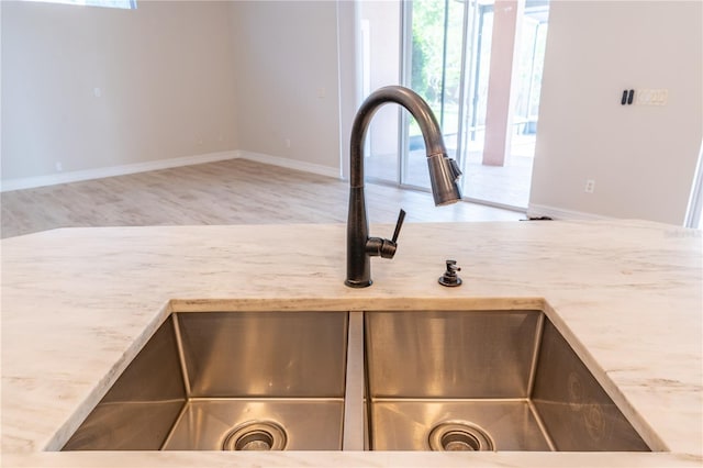 interior details featuring light stone counters, a sink, and baseboards