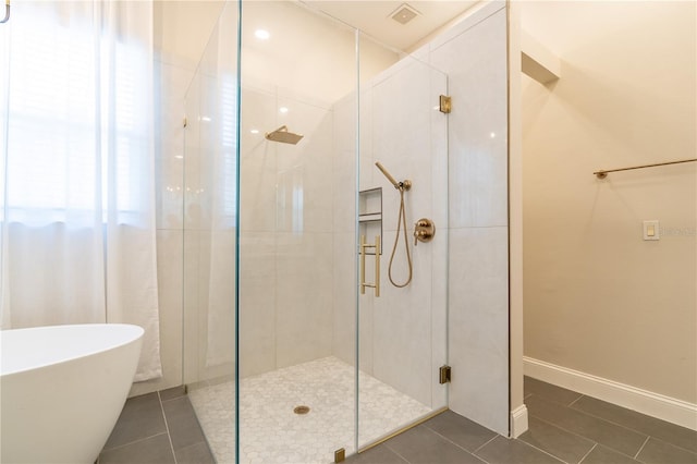 full bath with a stall shower, a soaking tub, tile patterned flooring, and baseboards