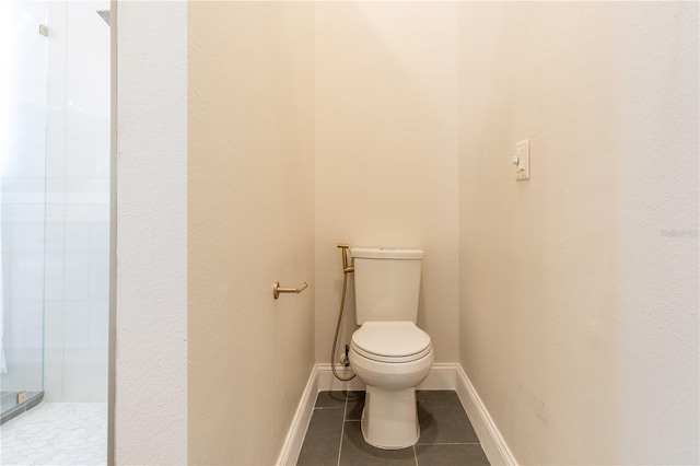 bathroom with toilet, tile patterned flooring, baseboards, and walk in shower