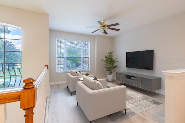 living area featuring light wood finished floors, baseboards, and a ceiling fan