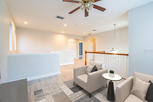 sitting room featuring light wood finished floors, visible vents, arched walkways, and recessed lighting