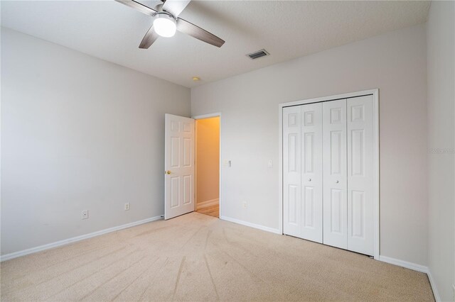 unfurnished bedroom with carpet, a closet, visible vents, a ceiling fan, and baseboards