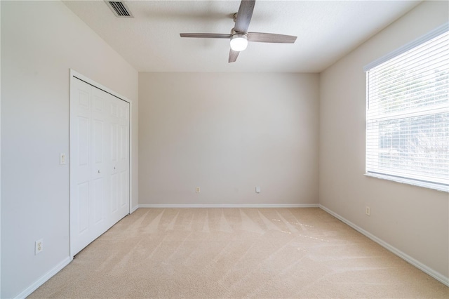 unfurnished bedroom with a closet, light carpet, visible vents, and baseboards